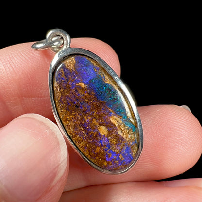 A handmade sterling silver pendant bezel set with an oval cut pipe boulder opal stone.