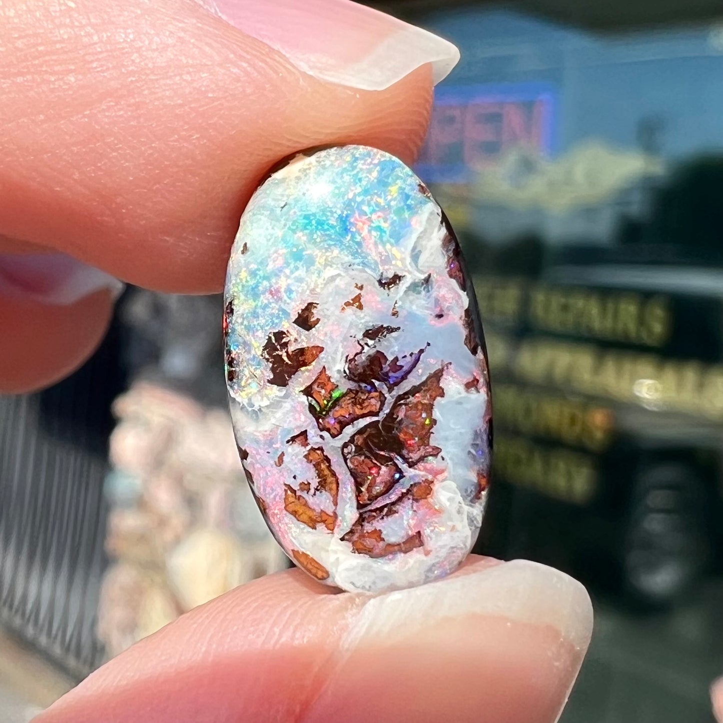 An oval cabochon cut boulder opal stone from Koroit, Australia.  The opal has a white body tone.