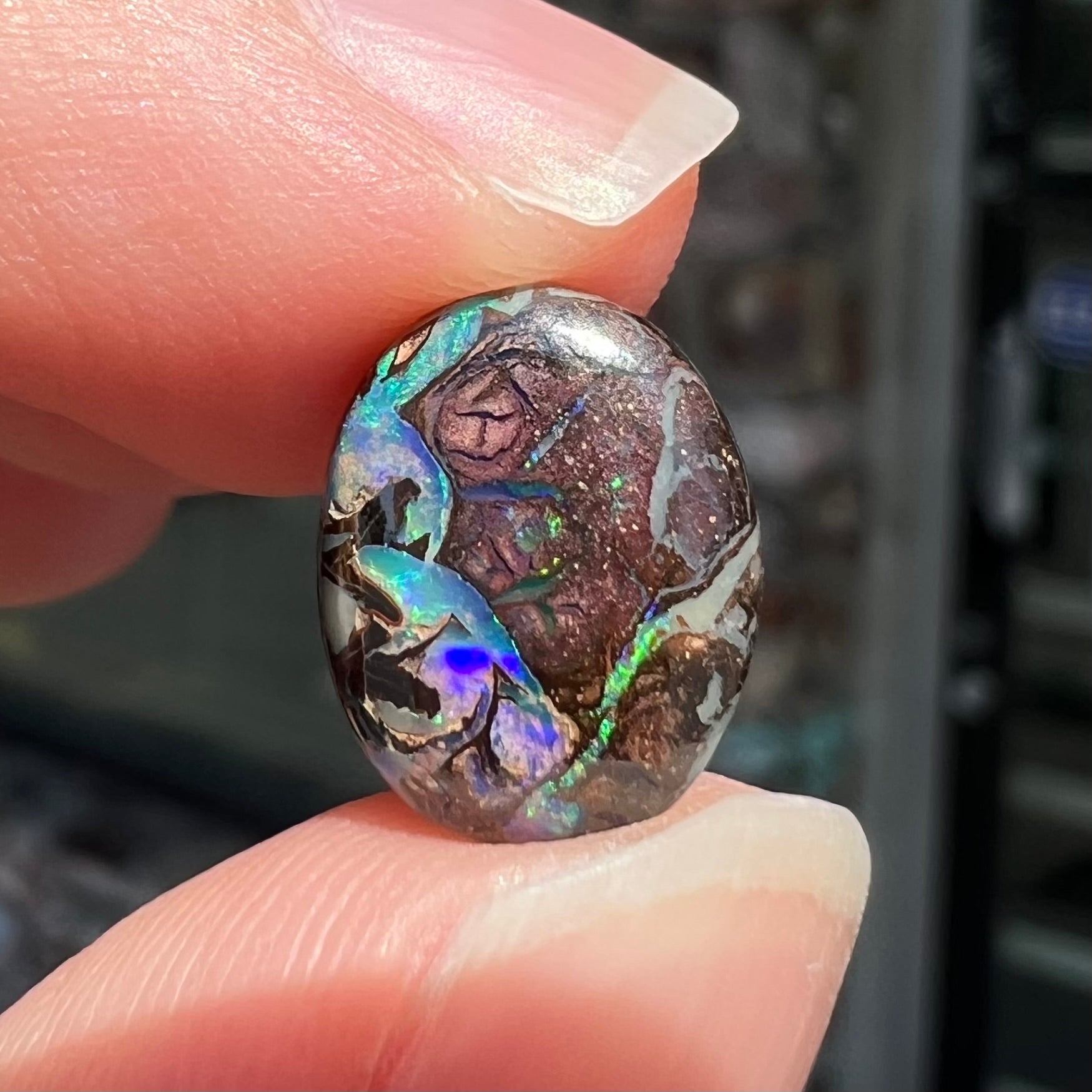 A loose, oval cabochon cut boulder opal stone from Koroit, Australia.  The opal has a bright green flash.