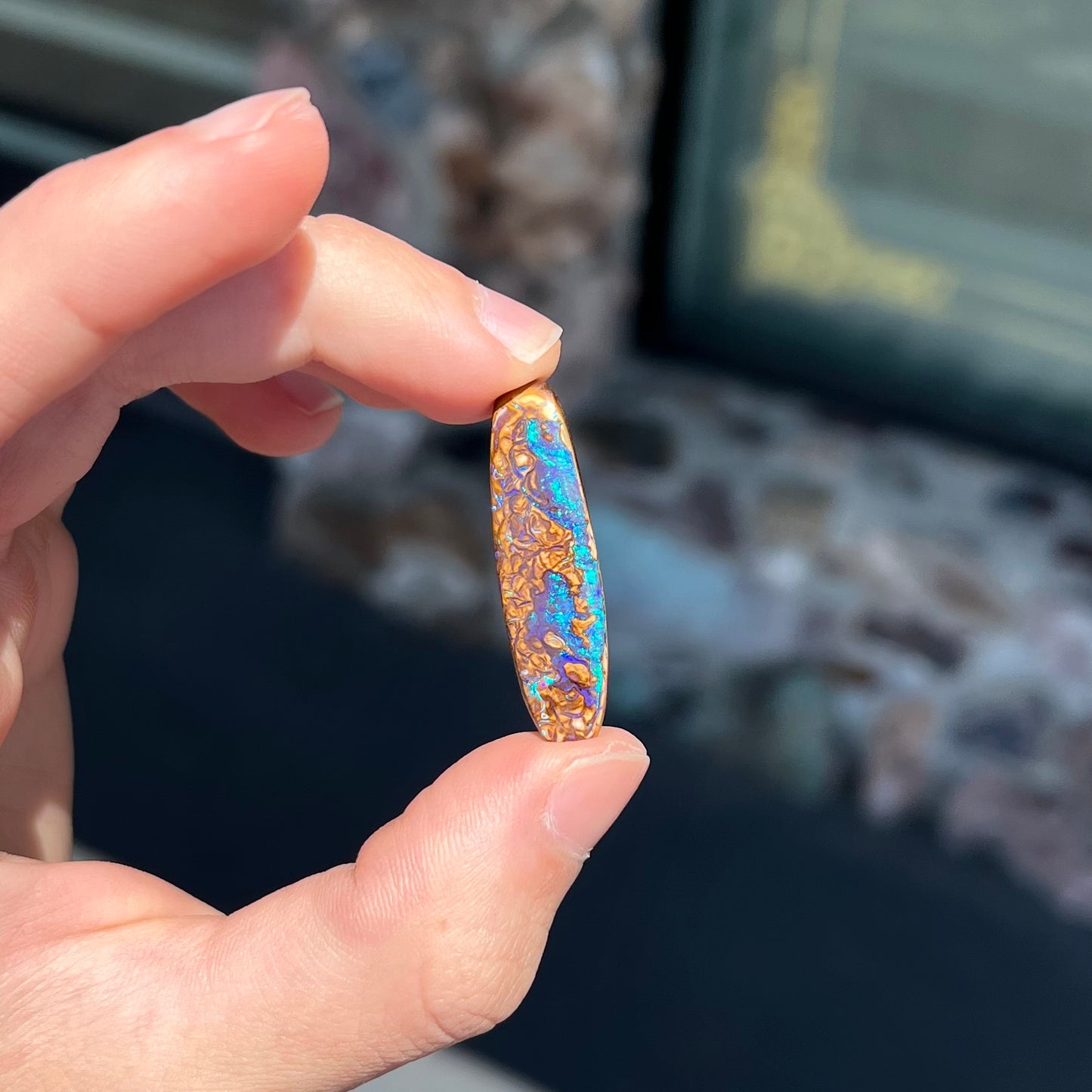 A polished boulder opal stone from Koroit, Australia.  The stone has blue and purple veins.