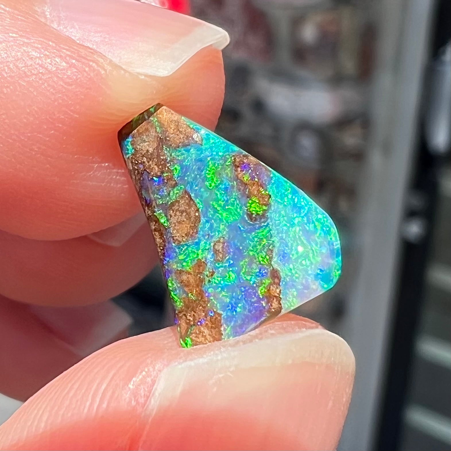 A loose boulder opal stone with bright green and blue fire.