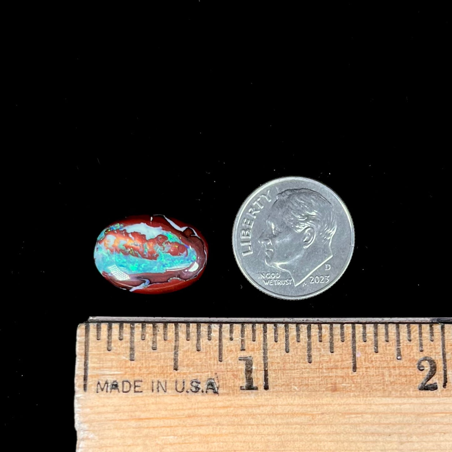 A loose, oval cabochon cut boulder opal stone from Australia.  The opal has blue and green veins in an ironstone matrix.