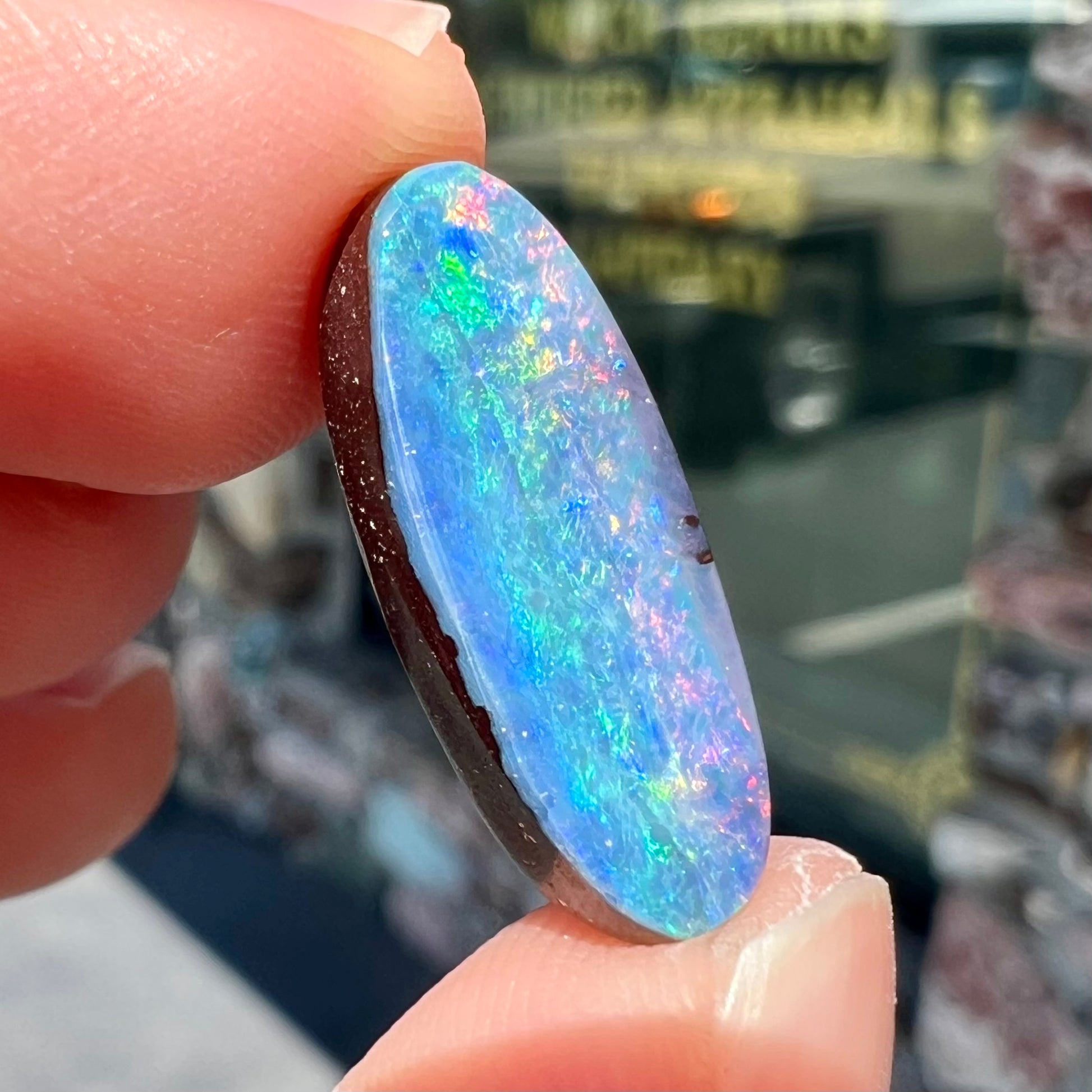 A loose, oval cut rainbow boulder opal gemstone.