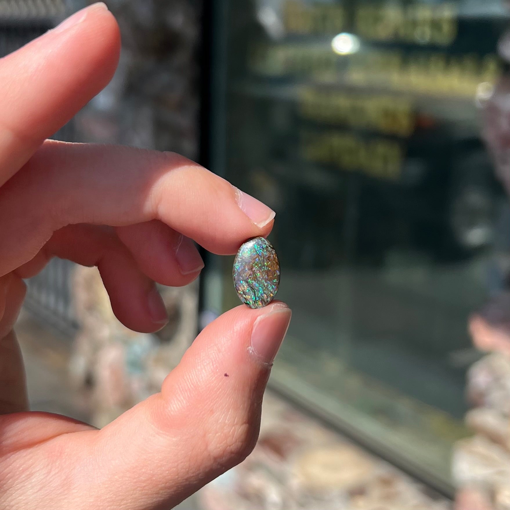 A loose, oval cabochon cut matrix boulder opal stone from Koroit, Australia.  The opal shines with green and blue colors.