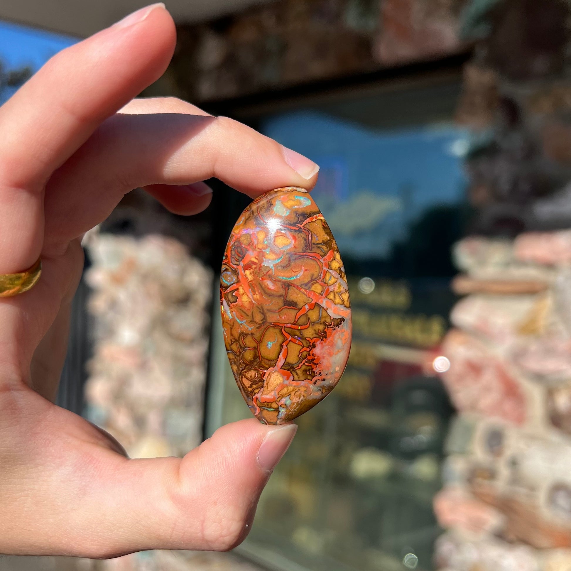 A polished boulder opal stone from Koroit, Australia.  The stone has been drilled with a bead hole.