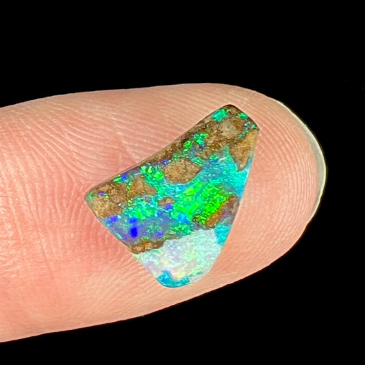 A loose boulder opal stone with bright green and blue fire.