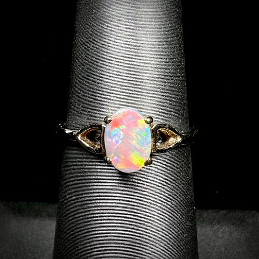 A dainty yellow gold ring mounted with a vivdly bright red Australian opal.  The ring has two heart shaped designs.