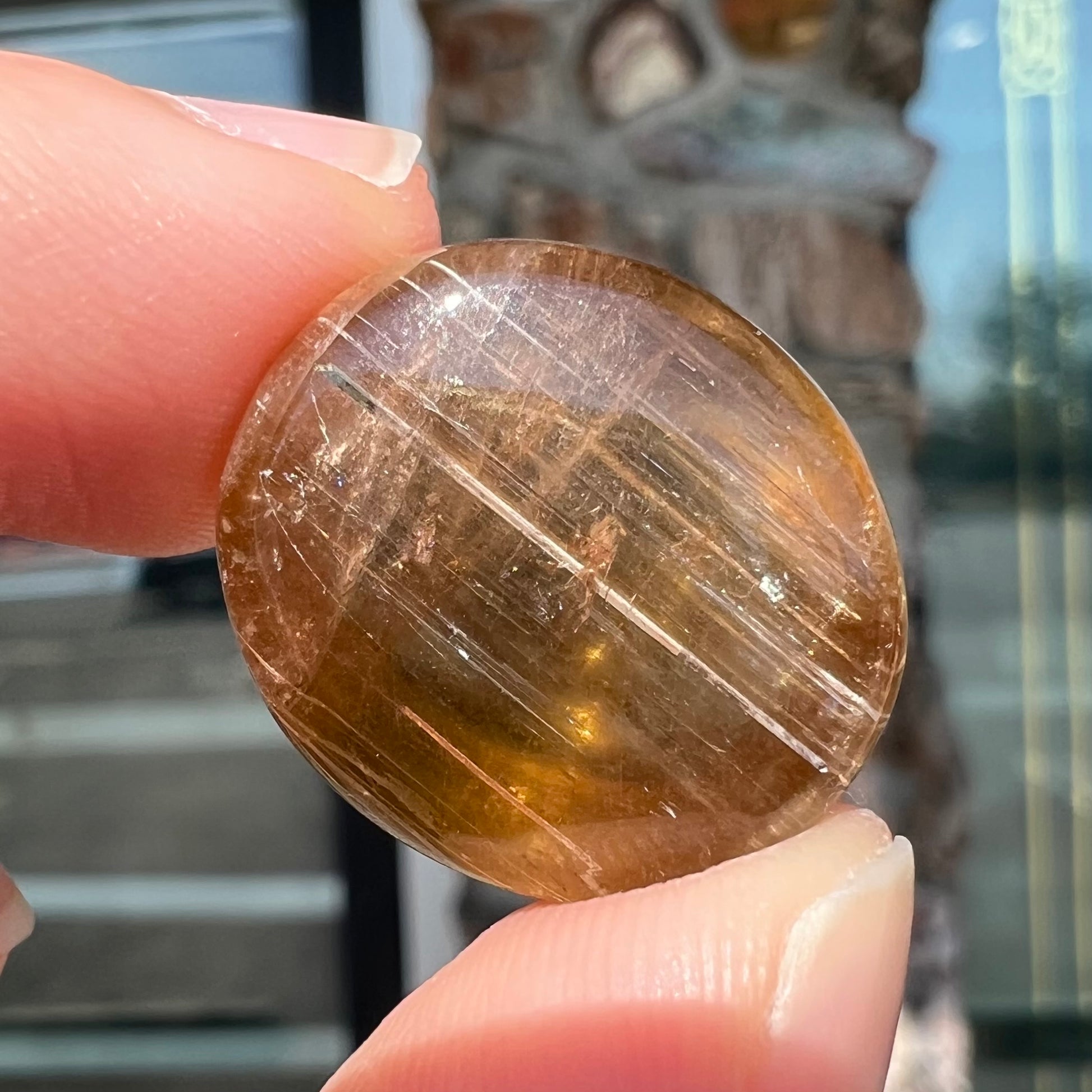 A loose, golden brown cat's eye dravite tourmaline gemstone.  The stone is cut into an oval shaped cabochon.