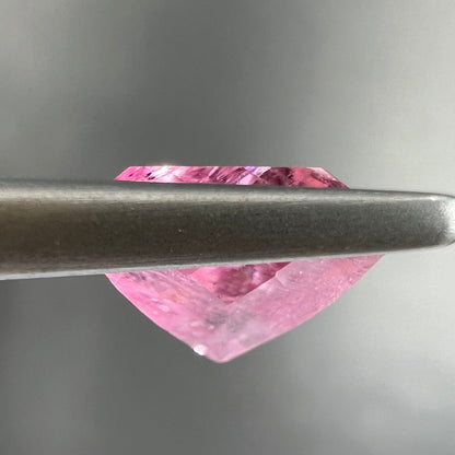 A loose, faceted trillion cut pink touramline gemstone.  The stone is a light bubblegum pink color.