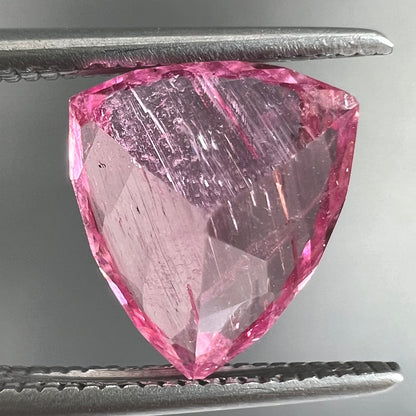 A loose, faceted trillion cut pink touramline gemstone.  The stone is a light bubblegum pink color.