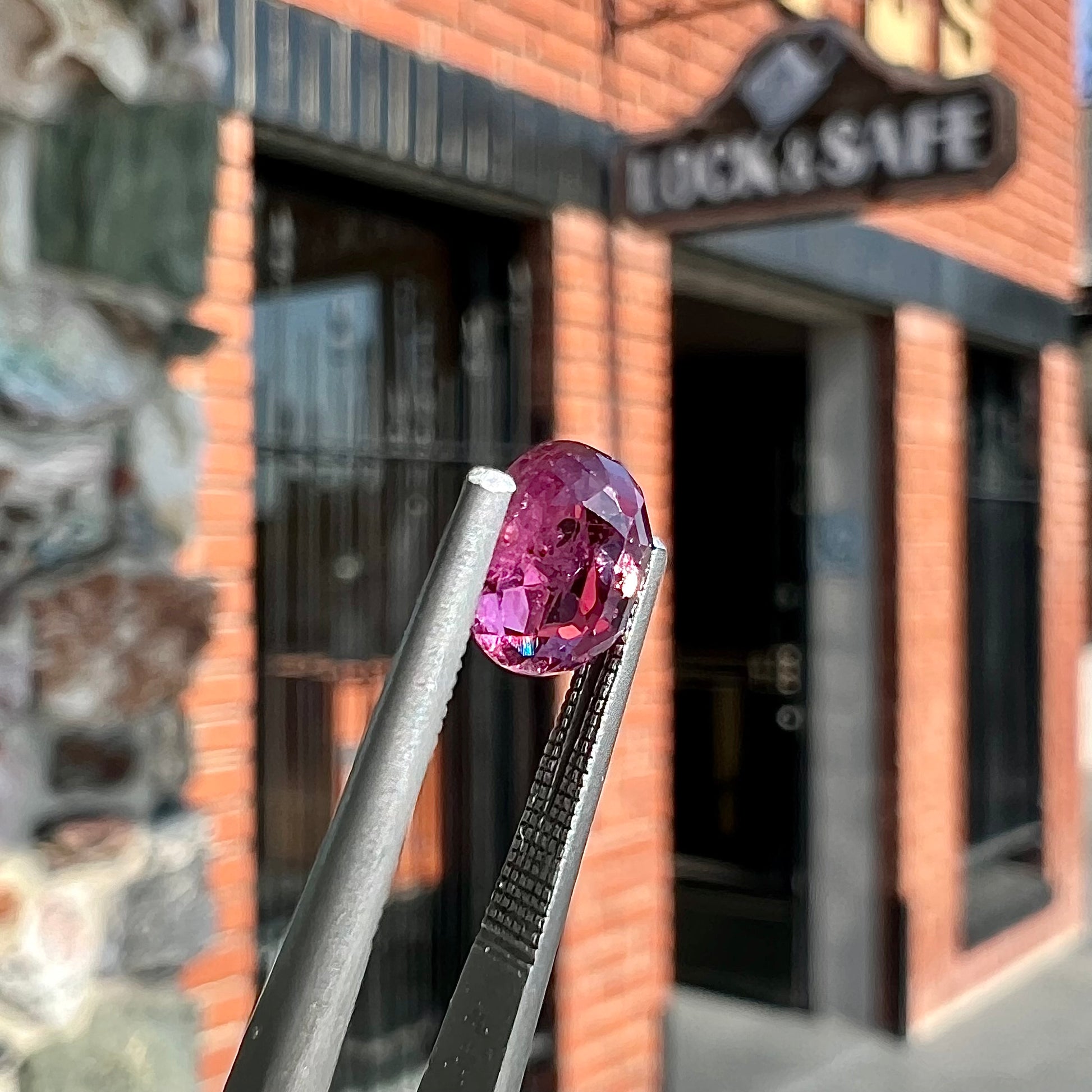 A loose, faceted oval cut natural purple sapphire.  The stone has a burst crystal inclusion.