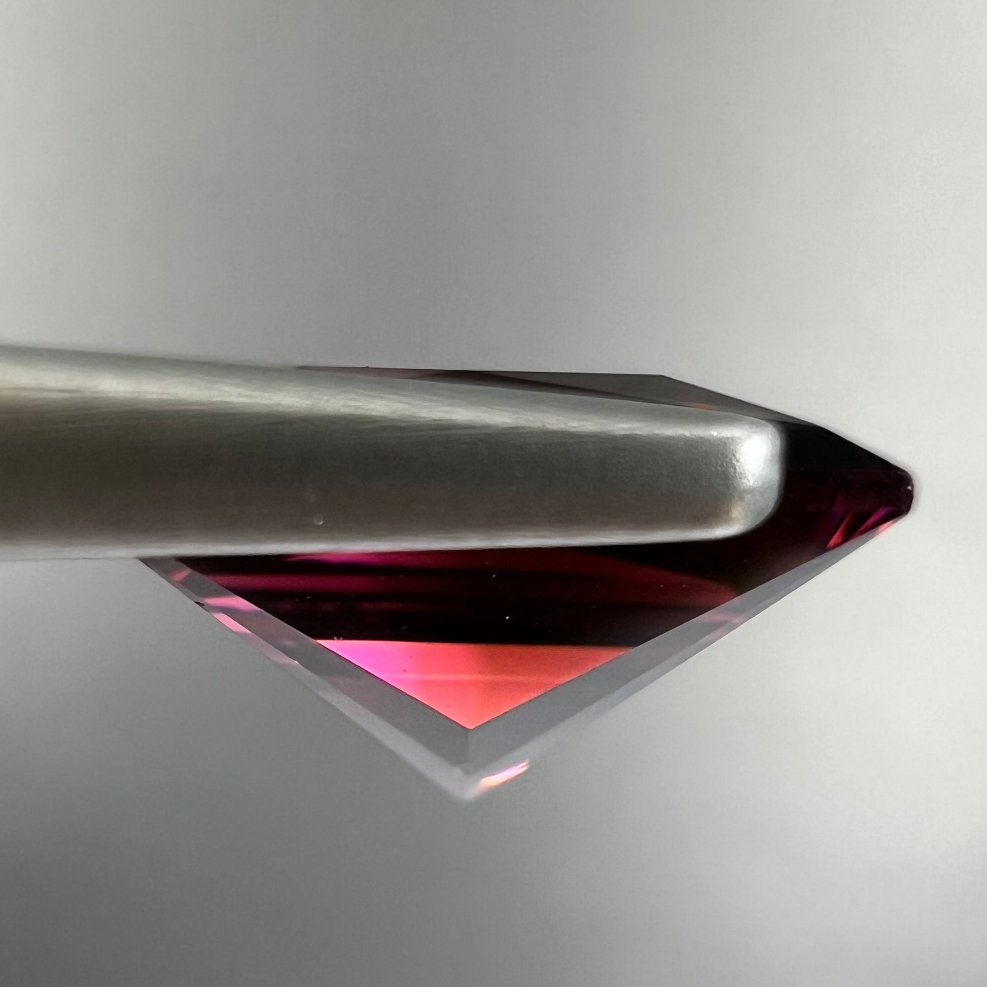 A loose, faceted princess cut tourmaline gemstone.  The stone is a burgundy purple color.