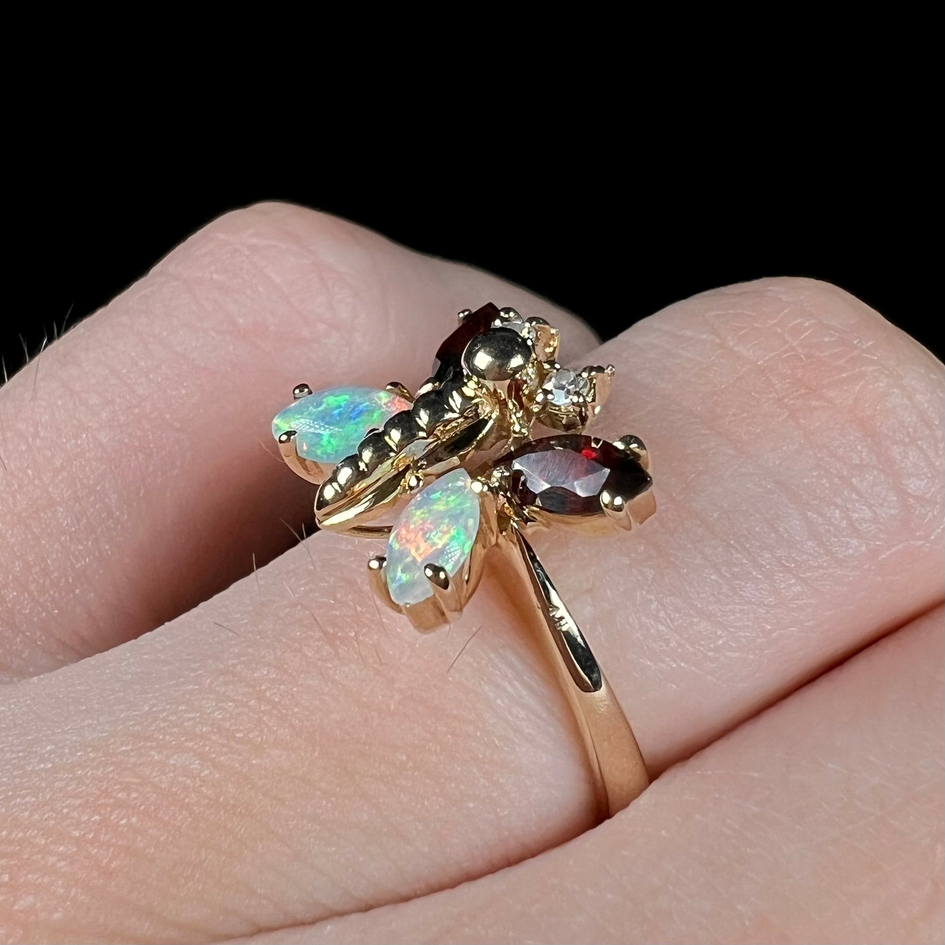 A yellow gold butterfly ring mounted with marquise cut garnets and opals and round diamond accents.