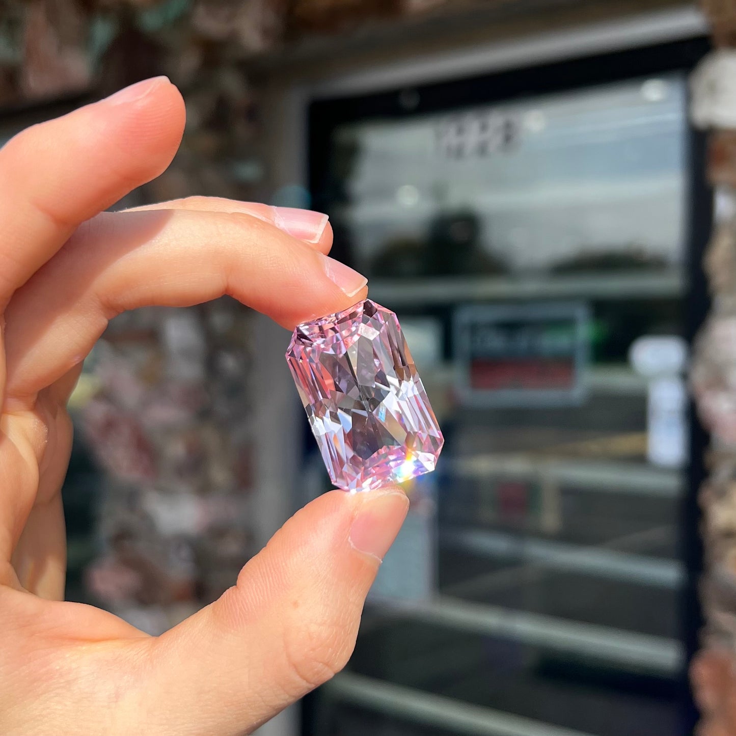 A loose, radiant cut kunzite gemstone.  The stone is a light purplish pink color.