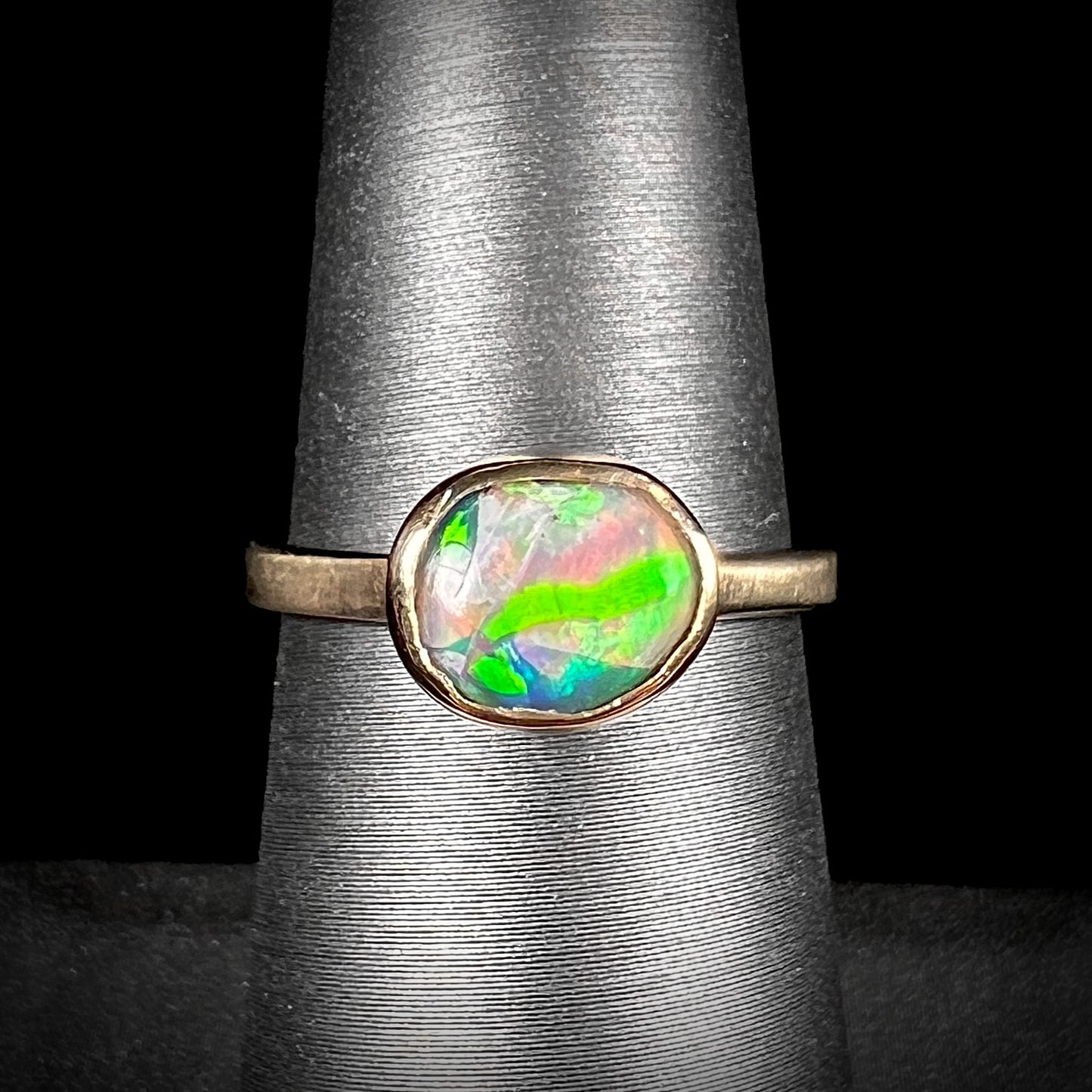 A yellow gold solitaire ring set with a natural Australian cat's eye opal stone.