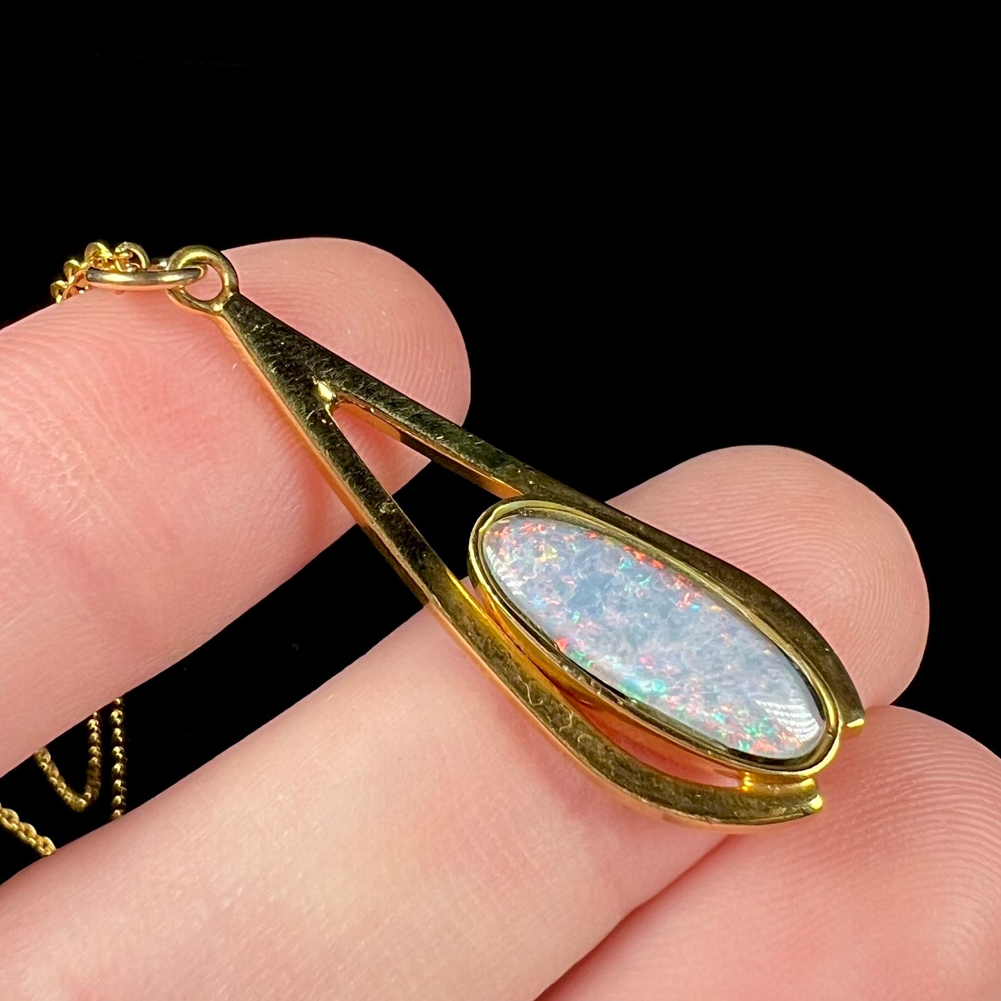 A yellow gold plated necklace set with an oval cut opal triplet.