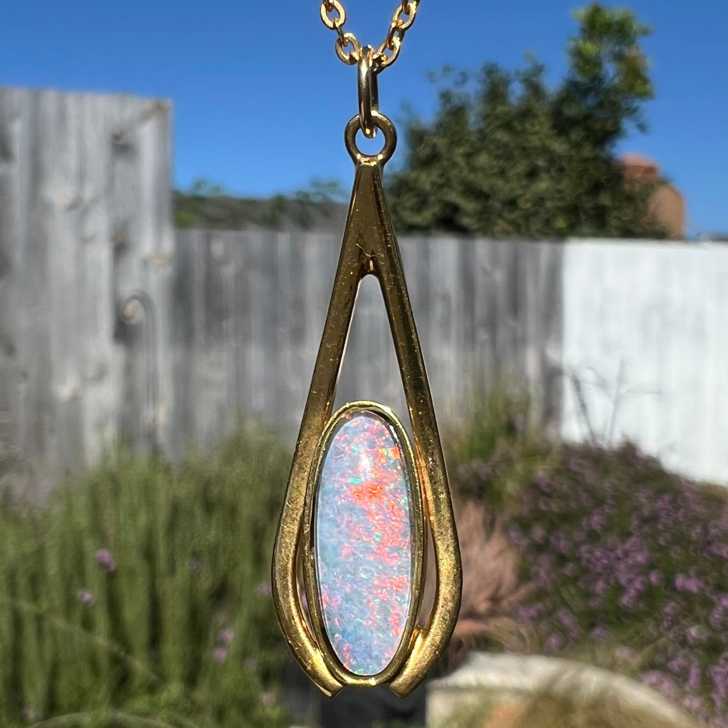 A yellow gold plated necklace set with an oval cut opal triplet.