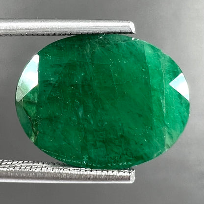 A loose, faceted oval cut commercial grade emerald stone.