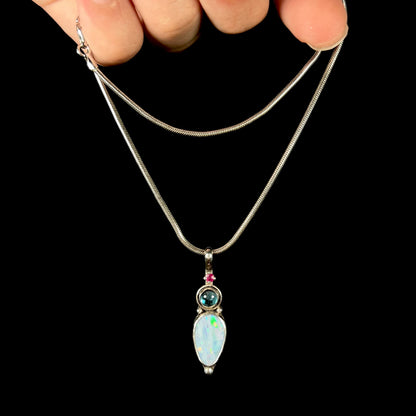 A sterling silver necklace shaped like a child, mounted with an opal doublet, a ruby, and a blue piece of glass.