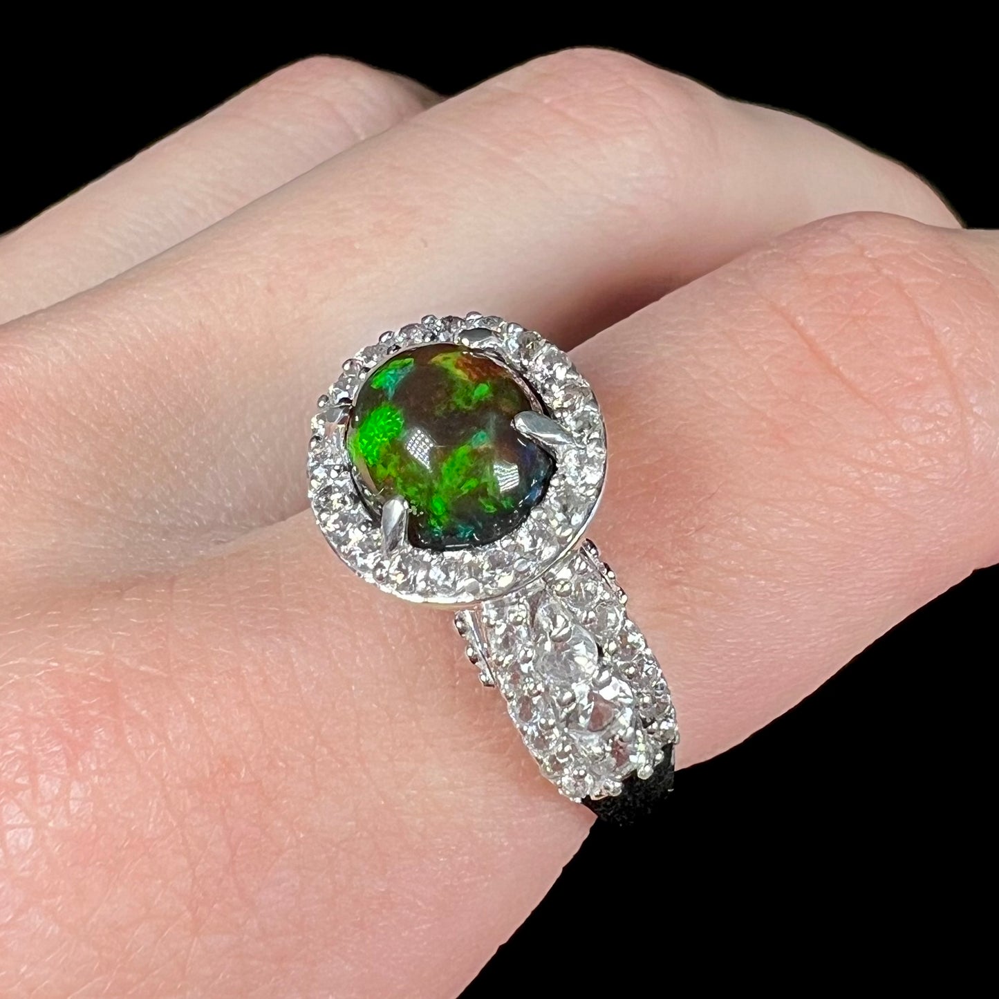 A CZ-accented sterling silver halo ring mounted with a smoked Ethiopian fire opal.  The opal plays green, red, and blue colors.