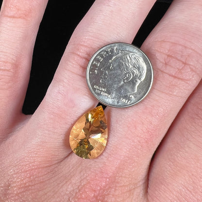 A loose, golden yellow, pear shaped citrine gemstone.