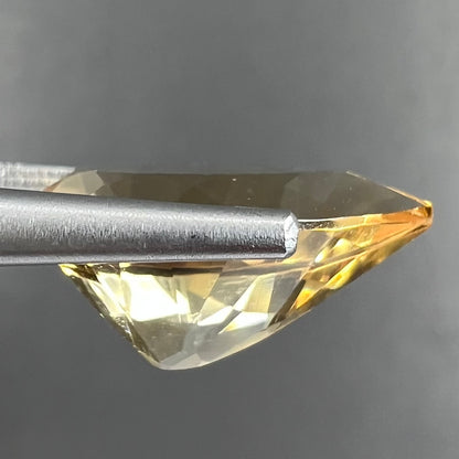 A loose, golden yellow, pear shaped citrine gemstone.