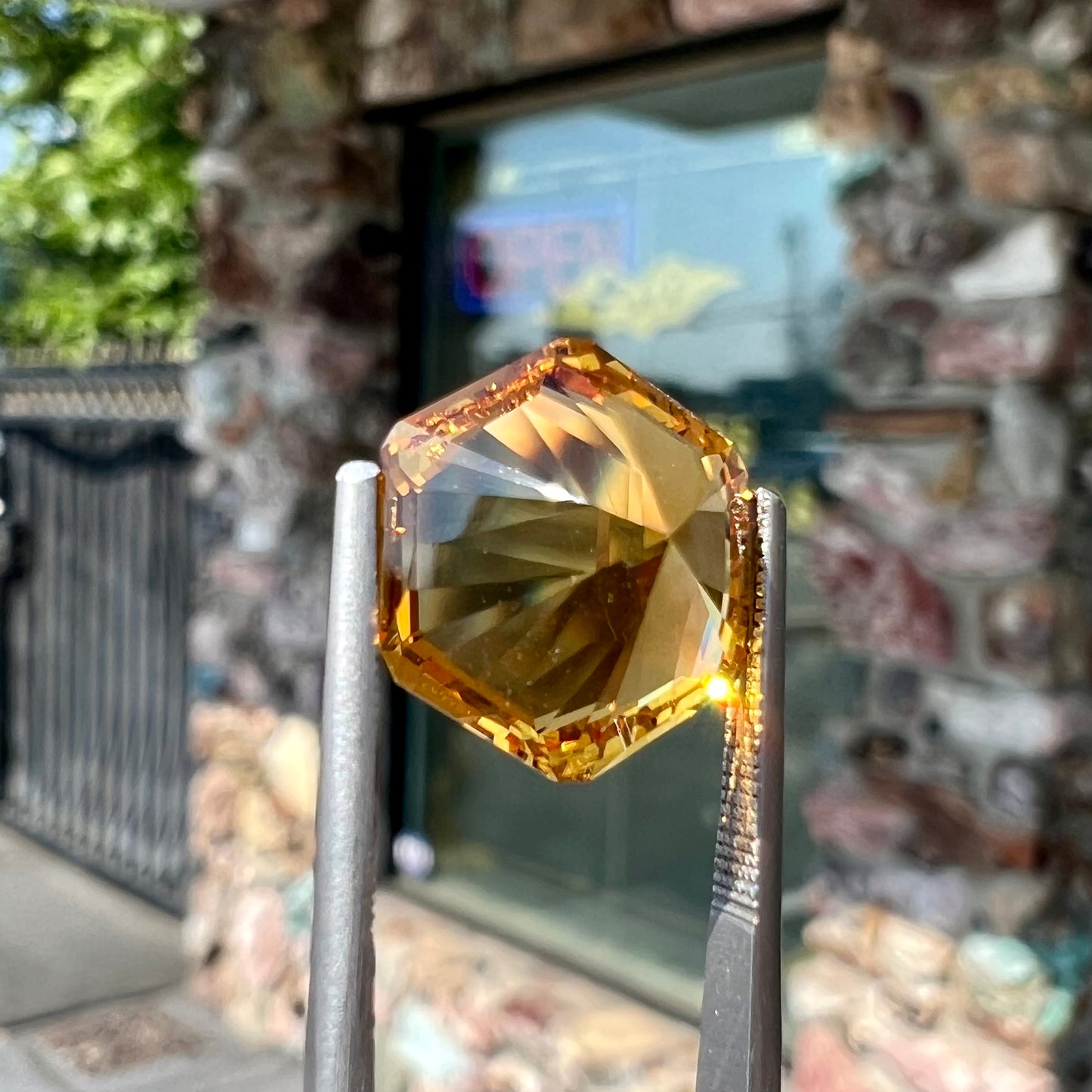 A loose, faceted hexagon cut citrine gem.  The stone is golden yellow color.