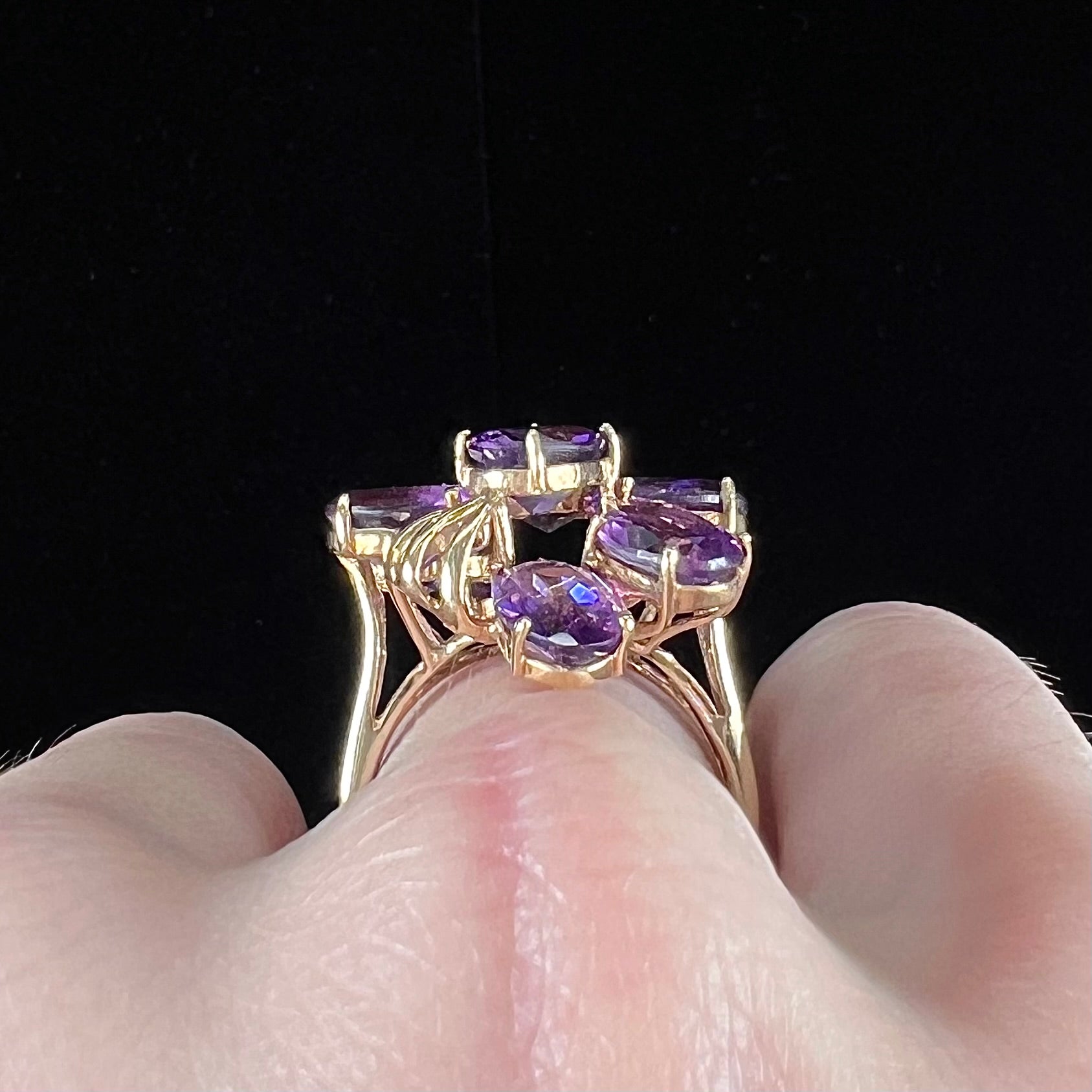 A cluster ring set with eight purple oval cut amethysts in yellow gold.