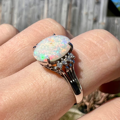 An Australian opal and diamond engagement ring in platinum.  The ring has filigree scrolling.