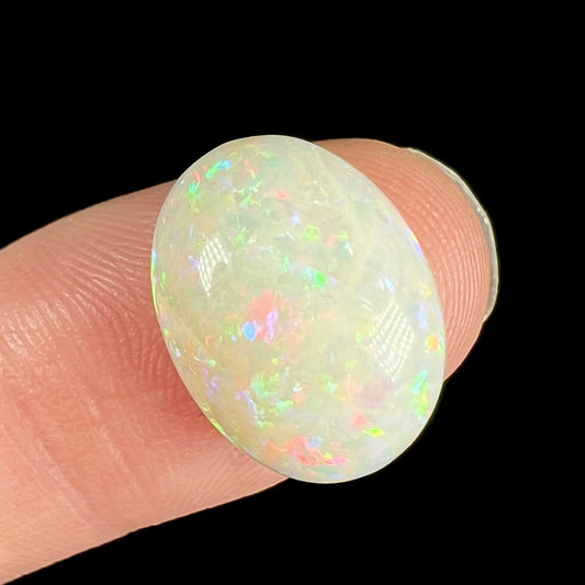 An oval cabochon cut white opal.  The opal has an eye-visible natural fissure inclusion.