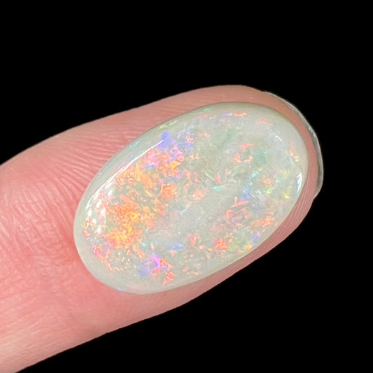 An oval cabochon cut opal from Coober Pedy, Australia.  The opal has predominantly red fire.