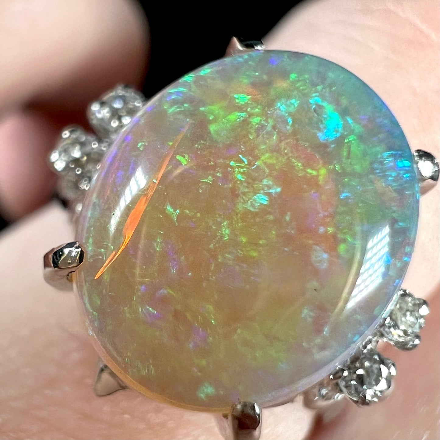 An Australian crystal opal and diamond engagement ring set in a platinum filigree mounting.  The opal plays green/blue colors and has a crack.