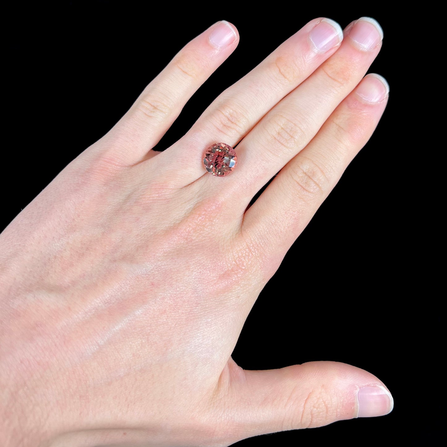 A loose, round brilliant checkerboard cut Zandrite gemstone.  The stone changes colors from greenish tan to purple.