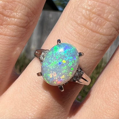 A platinum filigree opal engagement ring set with diamond accents.  The opal has green-blue colors.