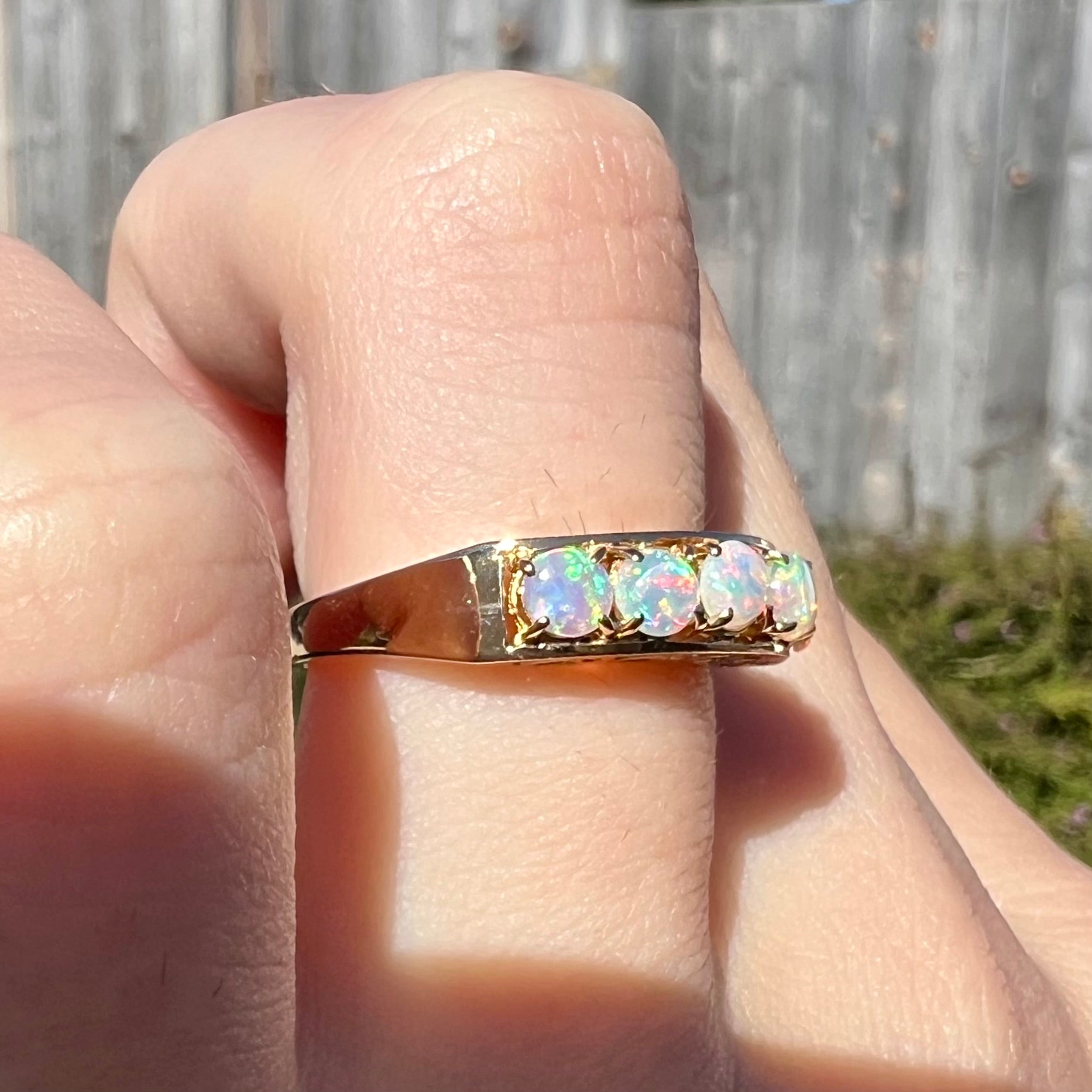 An 18 karat yellow gold line-style filigree ring mounted with five round, cabochon cut Australian crystal opals.