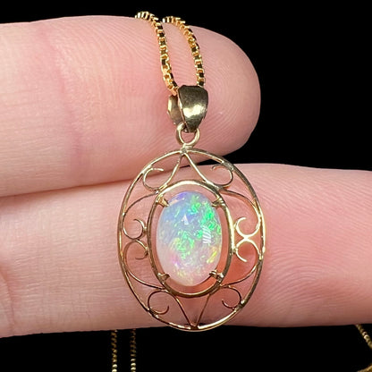 An 18 karat yellow gold filigree opal necklace.  The opal has bright green color play.