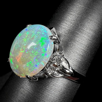 An Australian crystal opal and diamond engagement ring set in a platinum filigree mounting.  The opal plays green/blue colors and has a crack.