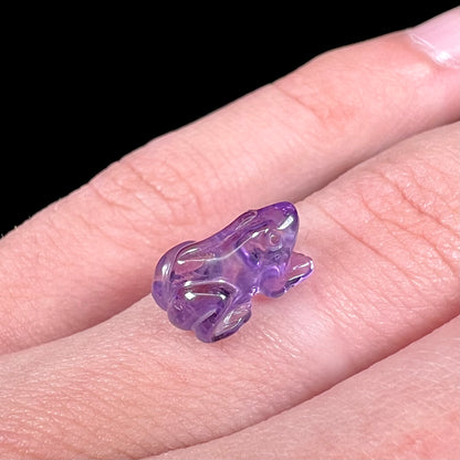 A stone frog carved from purple amethyst crystal.