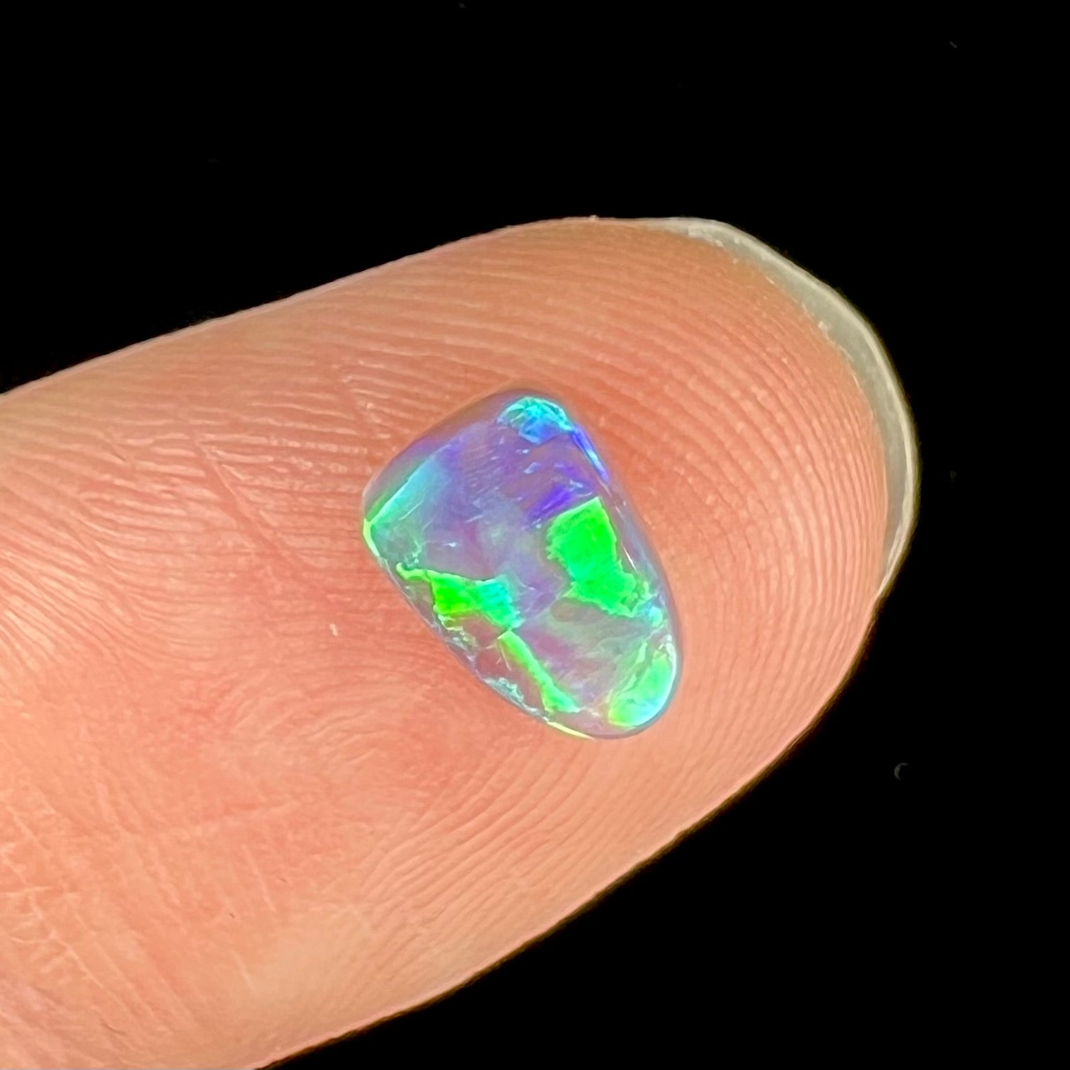 A semi-black crystal opal stone that shines green and blue colors.