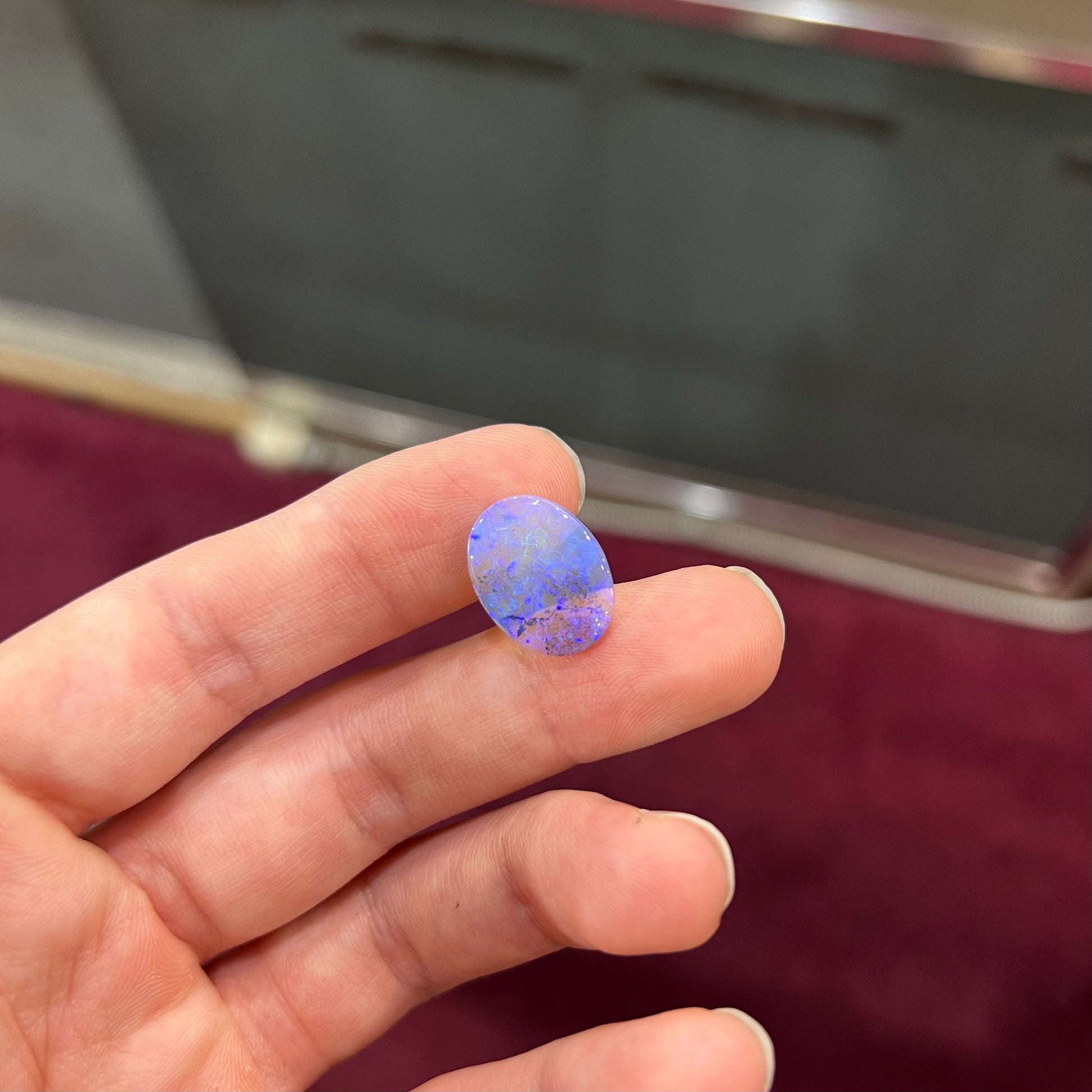 A loose, oval cabochon cut crystal opal from Lightning Ridge, Austalia that weighs 5.16 carats.  The stone has blue and purple colors.