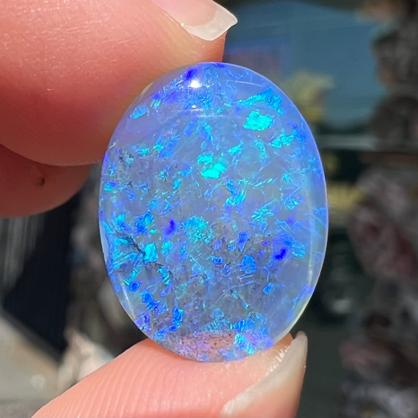 A loose, oval cabochon cut crystal opal from Lightning Ridge, Austalia that weighs 5.16 carats.  The stone has blue and purple colors.