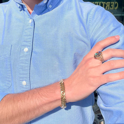 A yellow gold solitaire ring mounted with a Koroit boulder opal stone that shows the picture of a peacock.