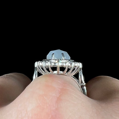 A ladies' white gold ring set with a faceted, heart shaped white moonstone, round moissanites, two aquamarine baguettes, and a marquise cut blue sapphire.