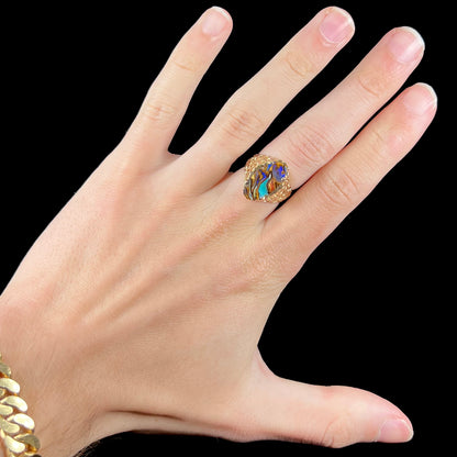 A yellow gold solitaire ring mounted with a Koroit boulder opal stone that shows the picture of a peacock.