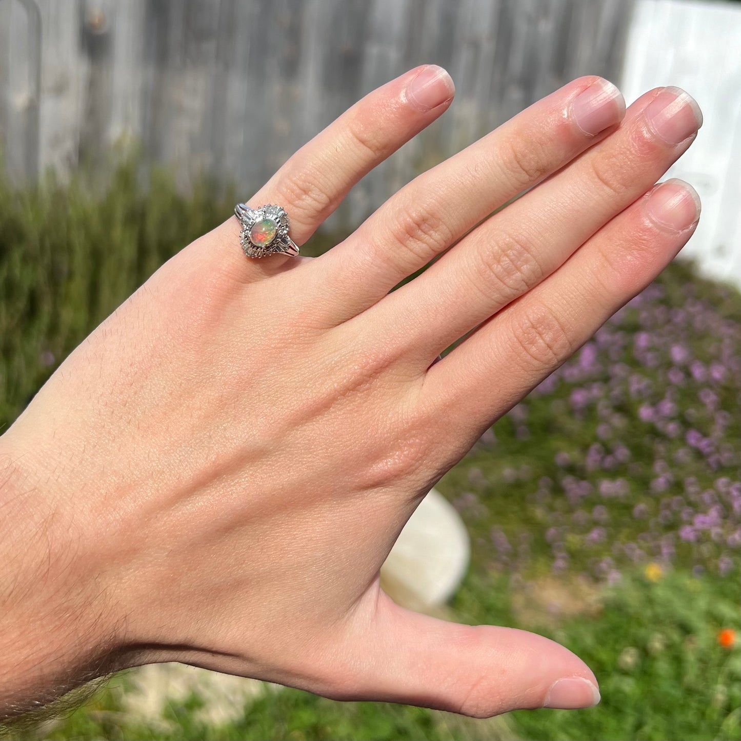 A platinum ring mounted with a Mexican fire opal and baguette cut diamond accents.