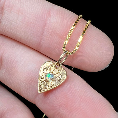 A yellow gold filigree heart necklace set with a round Australian crystal opal.  The opal has green fire.