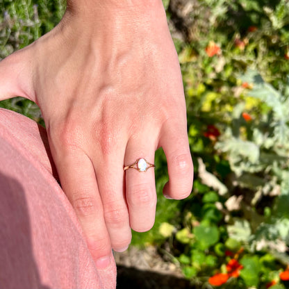 A ladies' simple opal solitaire ring.  The ring is yellow gold with a split shank.