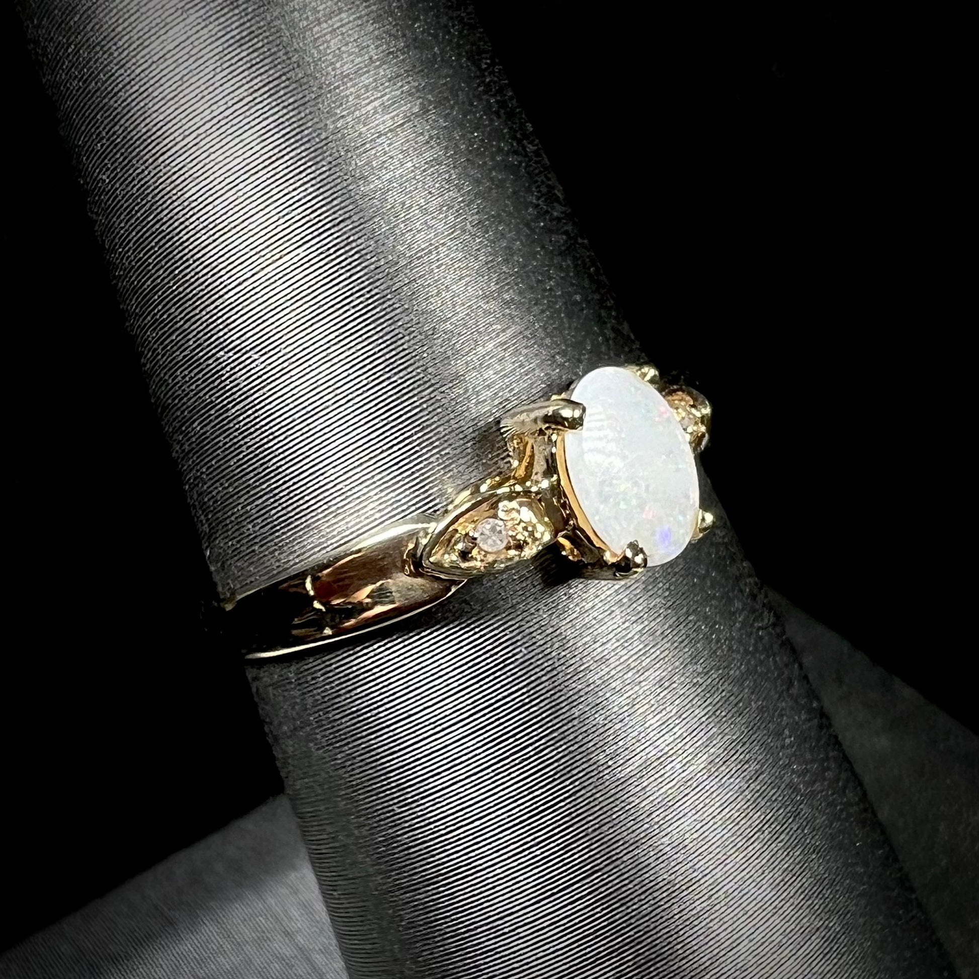 A dainty ladies' yellow gold opal and diamond ring.  The opal has subtle play of color.