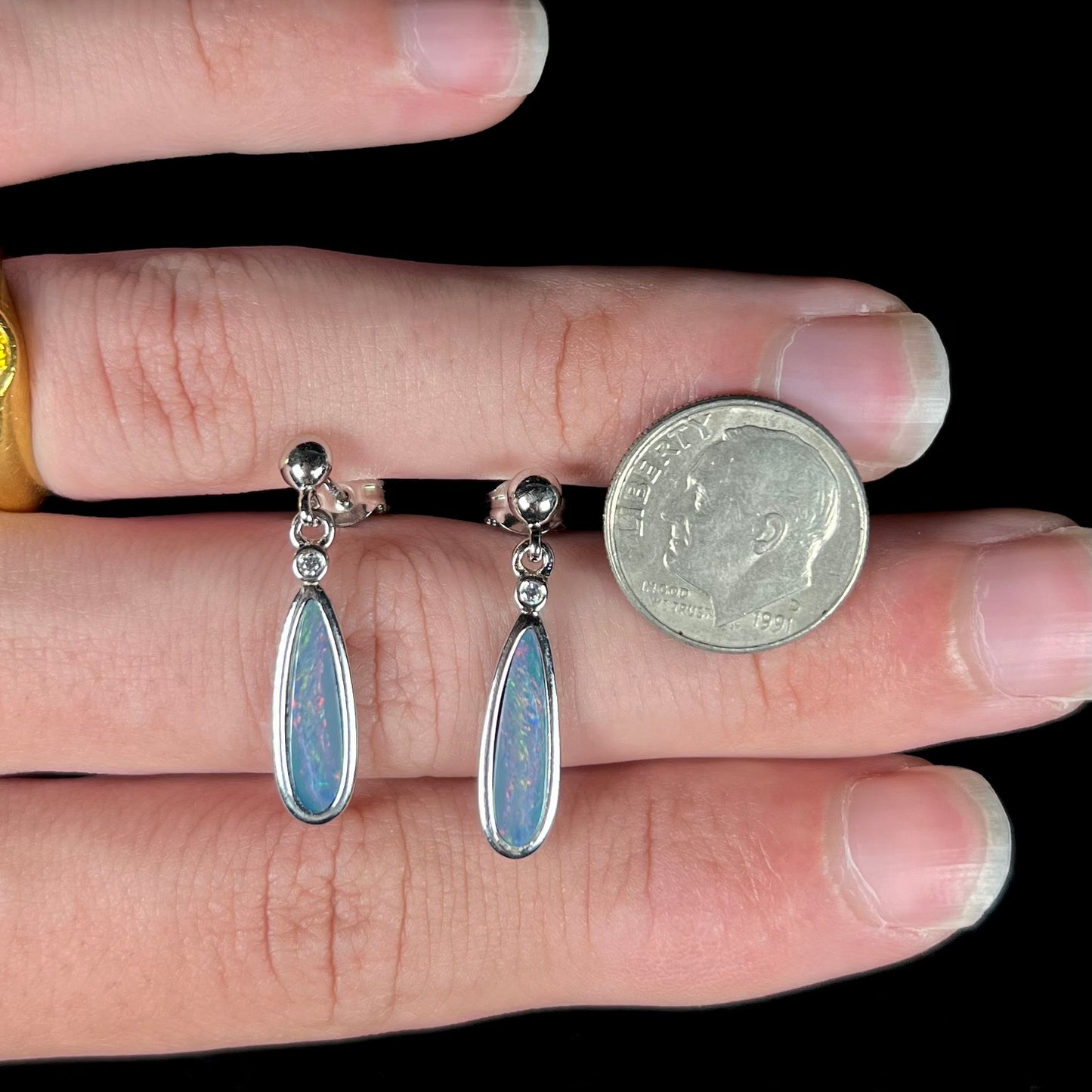 A pair of sterling silver, pear shaped opal doublet dangle earrings.  The opals have a gray body tone with red fire.