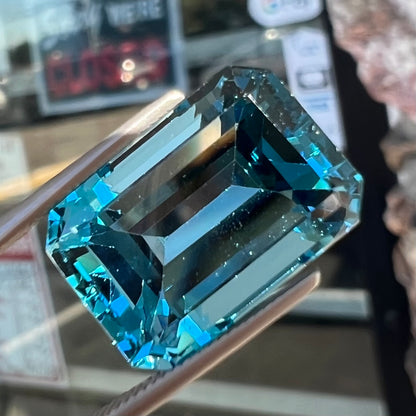 A loose, emerald cut London blue topaz gemstone.  The stone is a deep, dark blue color.